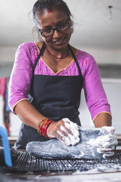 SHUS.dk håndværker vasker en brun uldtøffel med naturgummisål under produktionen i Nepal
